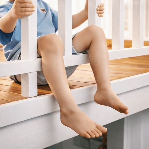 barriere-pour-enfant-garcon-assis-jambes-pendantes-entre-barreaux-bois-gardien-calme