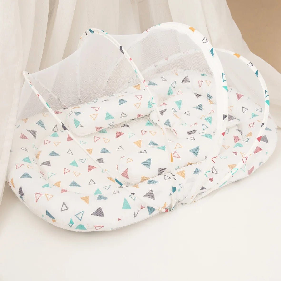 couffin-reducteur-de-lit-motif-triangles-multicolores-doux-moustiquaire-ouverte-ruisseau-tranquille