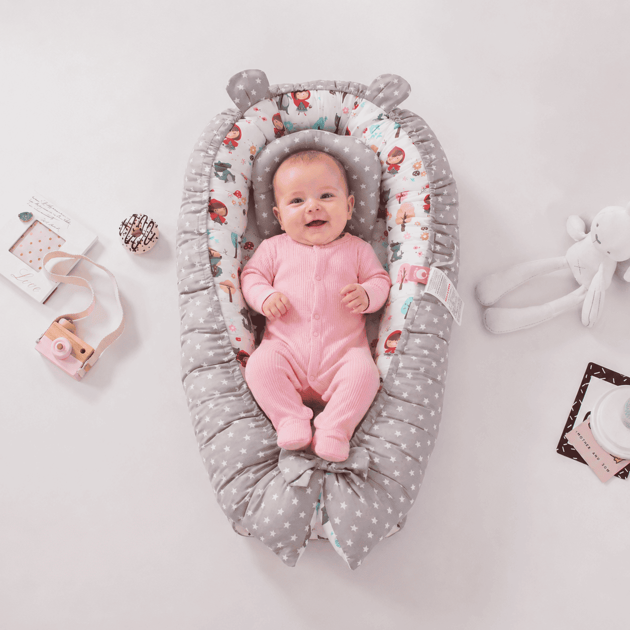 reducteur-de-lit-bebe-confort-rose-jouets-autour-nid-securisant-chambre-douce-sommeil-douceur