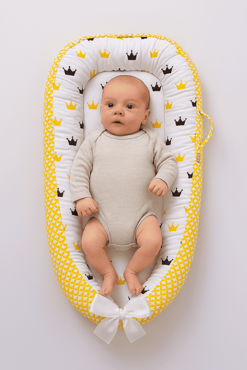 reducteur-de-lit-jaune-fond-blanc-motif-couronne-bebe-eveille-dedans-doudinid