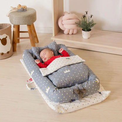 reducteur-de-lit-jollein-bebe-endormi-sur-nid-gris-motifs-couronnes-ecrin-de-serenite