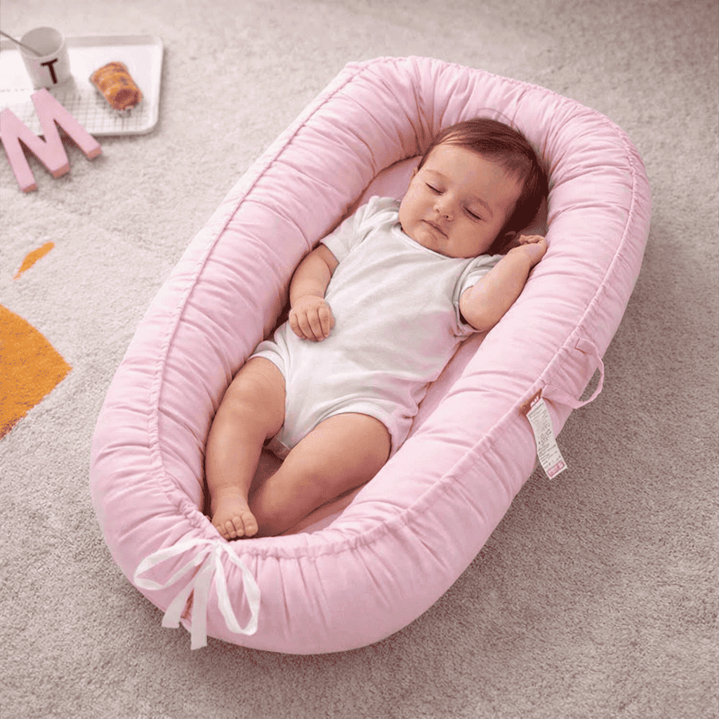 reducteur-de-lit-pour-bebe-bebe-allonge-dans-coussin-rose-confortable-berce-calin